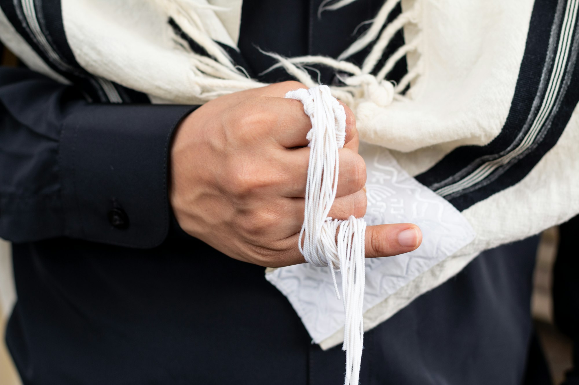 Tzitzit wrapped around a little finger to chant V'zot Hatorah. This is the Torah.