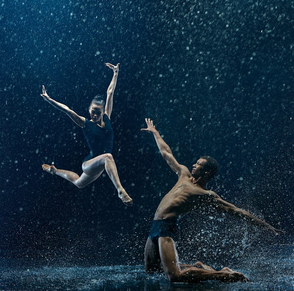 Young couple of ballet dancers dancing unde rwater drops