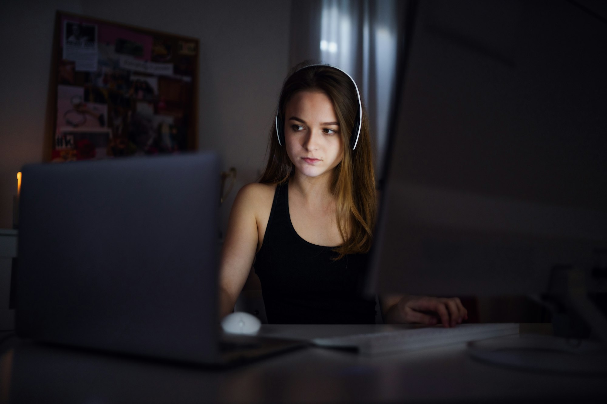 Bored young girl with computer sitting indoors, online chatting concept