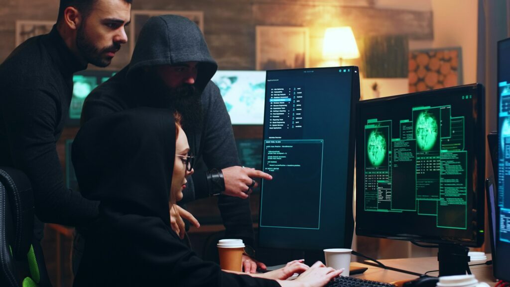 Team of hackers looking at computer with multiple monitors