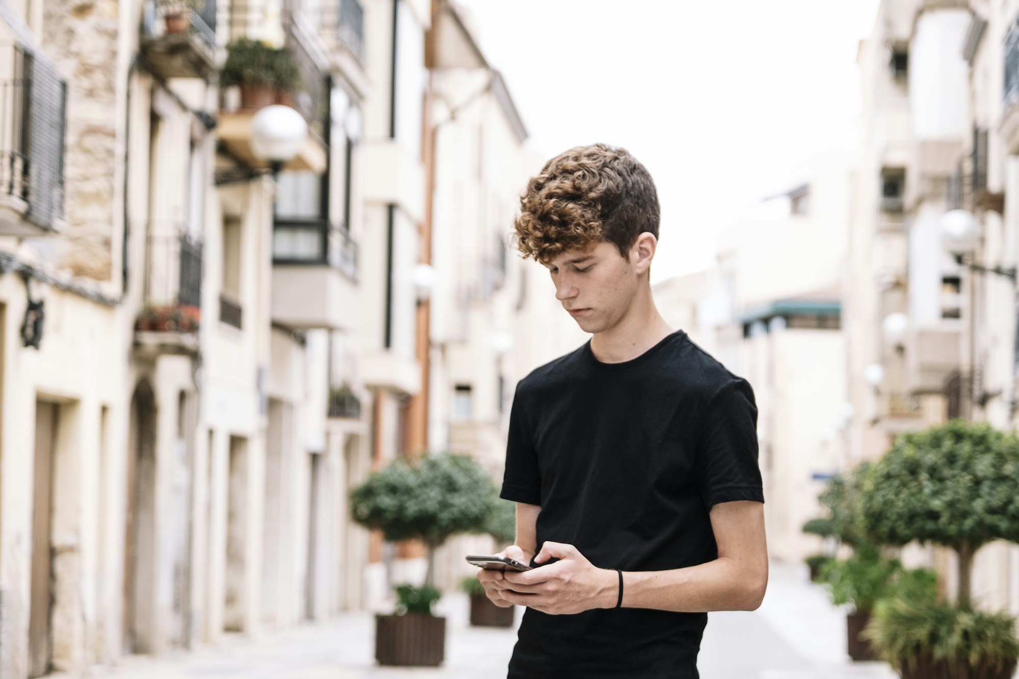 Teen boy with curly hair looking at the phone