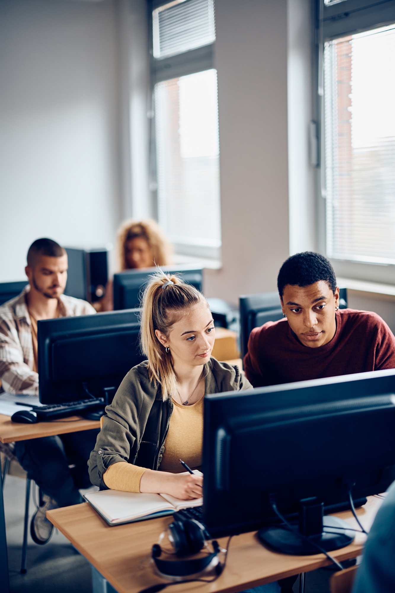 Young students cooperating while e-learning during computer class at the university.