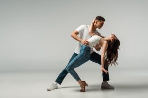 dancers in denim jeans dancing bachata on grey background